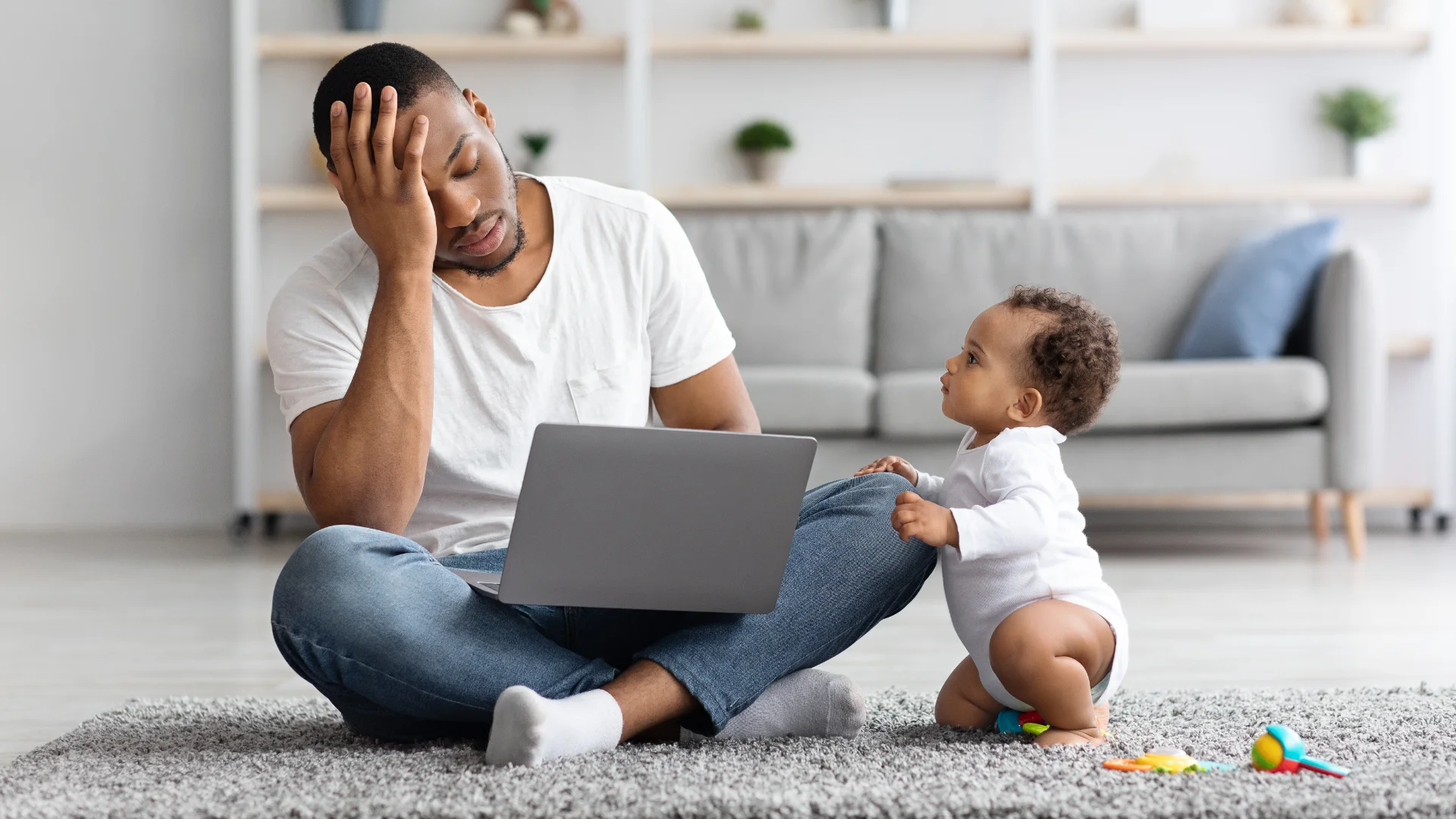 Stressed businessperson juggling a baby and laptop, symbolising high-maintenance websites.